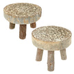 Two rustic wooden stools with round cream and brown patterned tops and short natural branch legs on white.