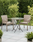 Natural rattan bistro garden furniture set with a chair and table from Pacific Lifestyle Ltd, shown outdoors in a garden setting.