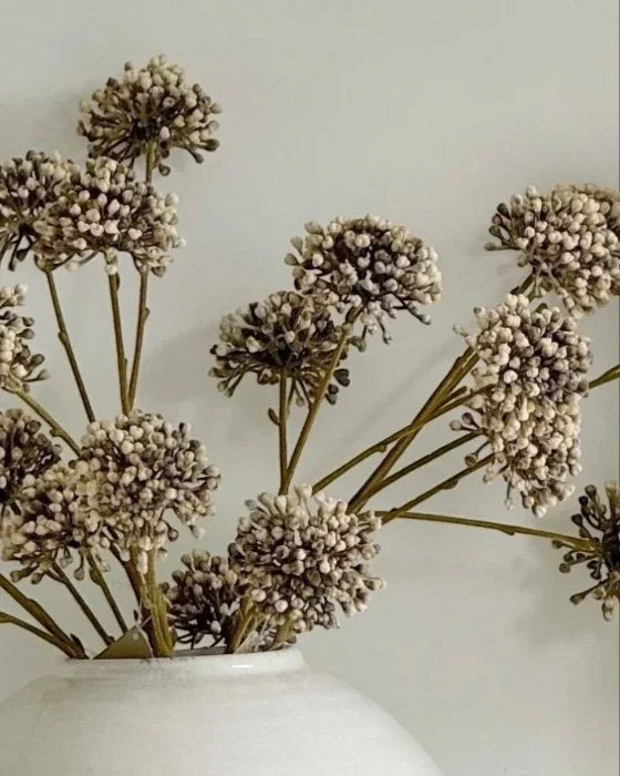 Decorative dried flowers in a white vase against a light background