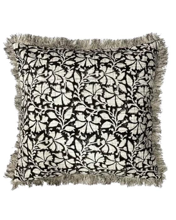 Decorative pillow with black floral pattern and fringes on a white background