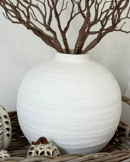 White textured vase with branches and small pumpkins on a neutral background