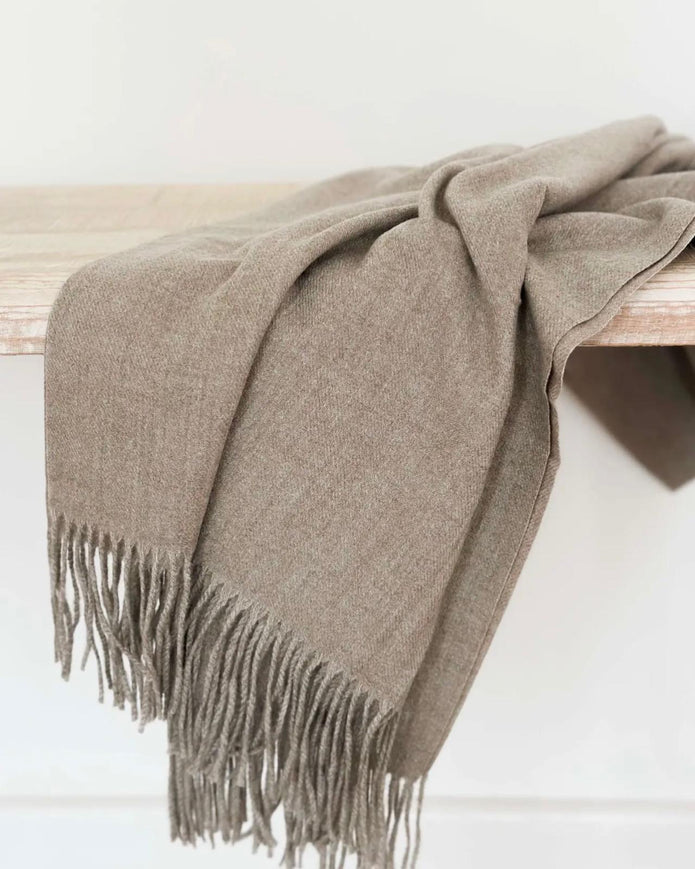 Beige and brown fine knit tasseled throw blanket by Ellenvale Trade for soft furnishings, shown draped over a cozy sofa.