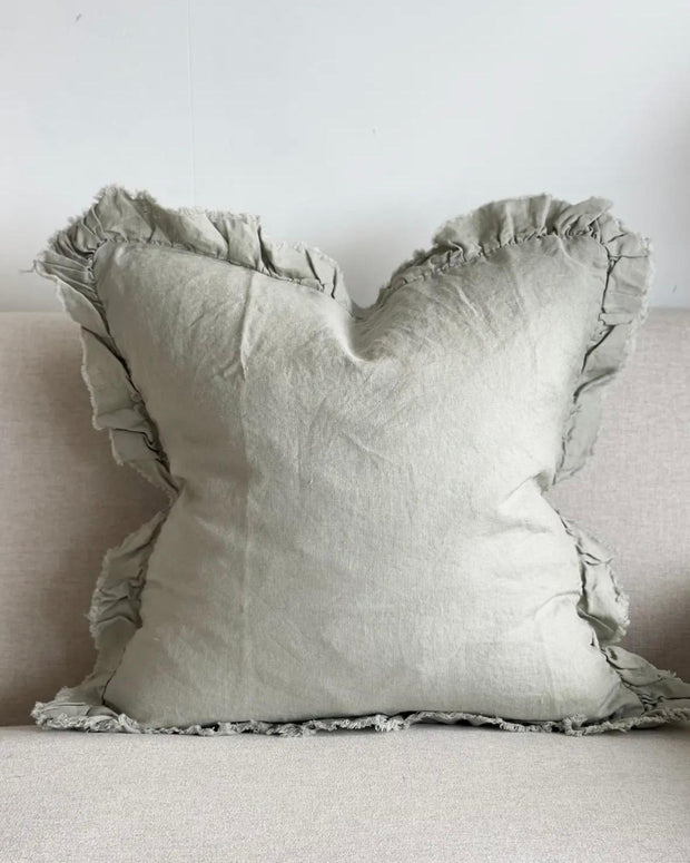 Sage green linen cushion cover with ruffled edges, soft furnishings by Ellenvale Trade, shown with decorative pillows.