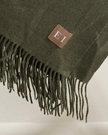 Olive green fine knit tasselled throw blanket by Ellenvale Trade, showcasing soft, cozy textile with tassel details.