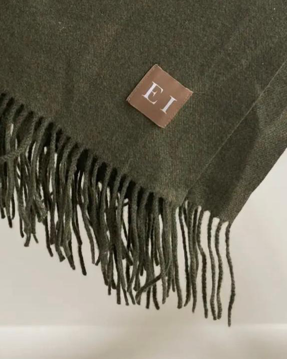 Olive green fine knit tasselled throw blanket by Ellenvale Trade, showcasing soft, cozy textile with tassel details.