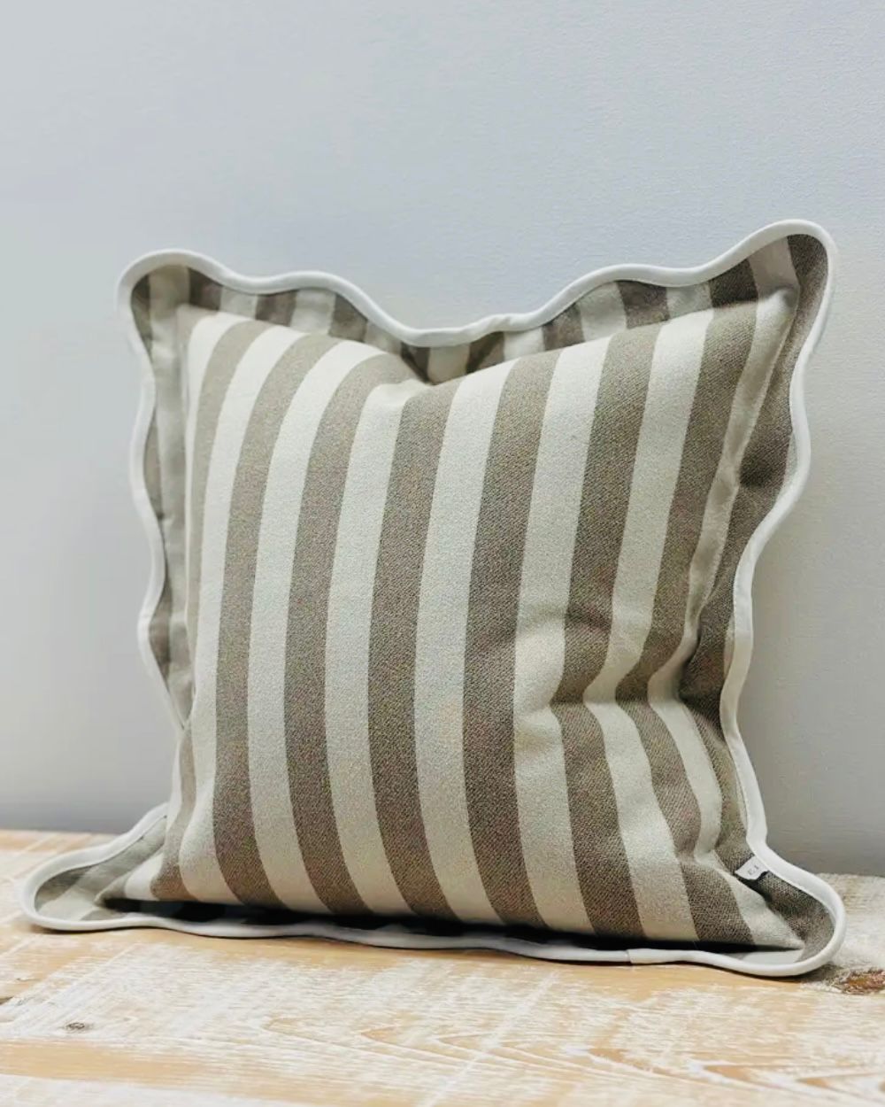 Beige square cushion cover with stripe and scalloped edges, soft furnishings by Ellenvale Trade, shown on a decorative pillow.