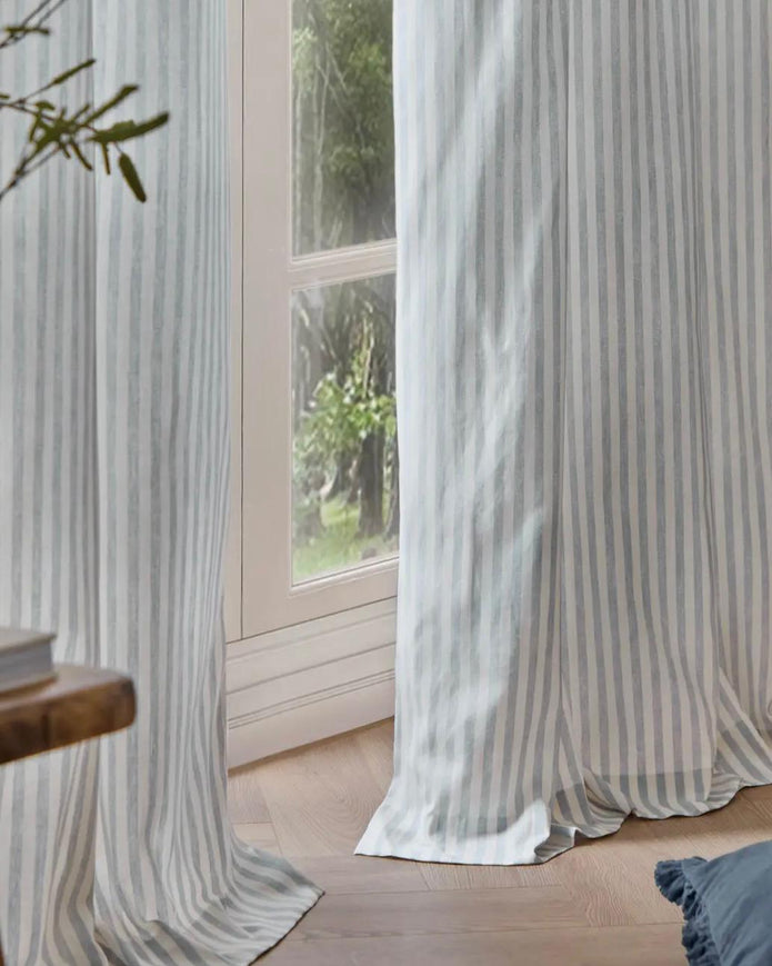 Riva Home Yard Ocean Blue striped blackout eyelet curtains hanging in a window, soft furnishings with bold blue and black stripes.