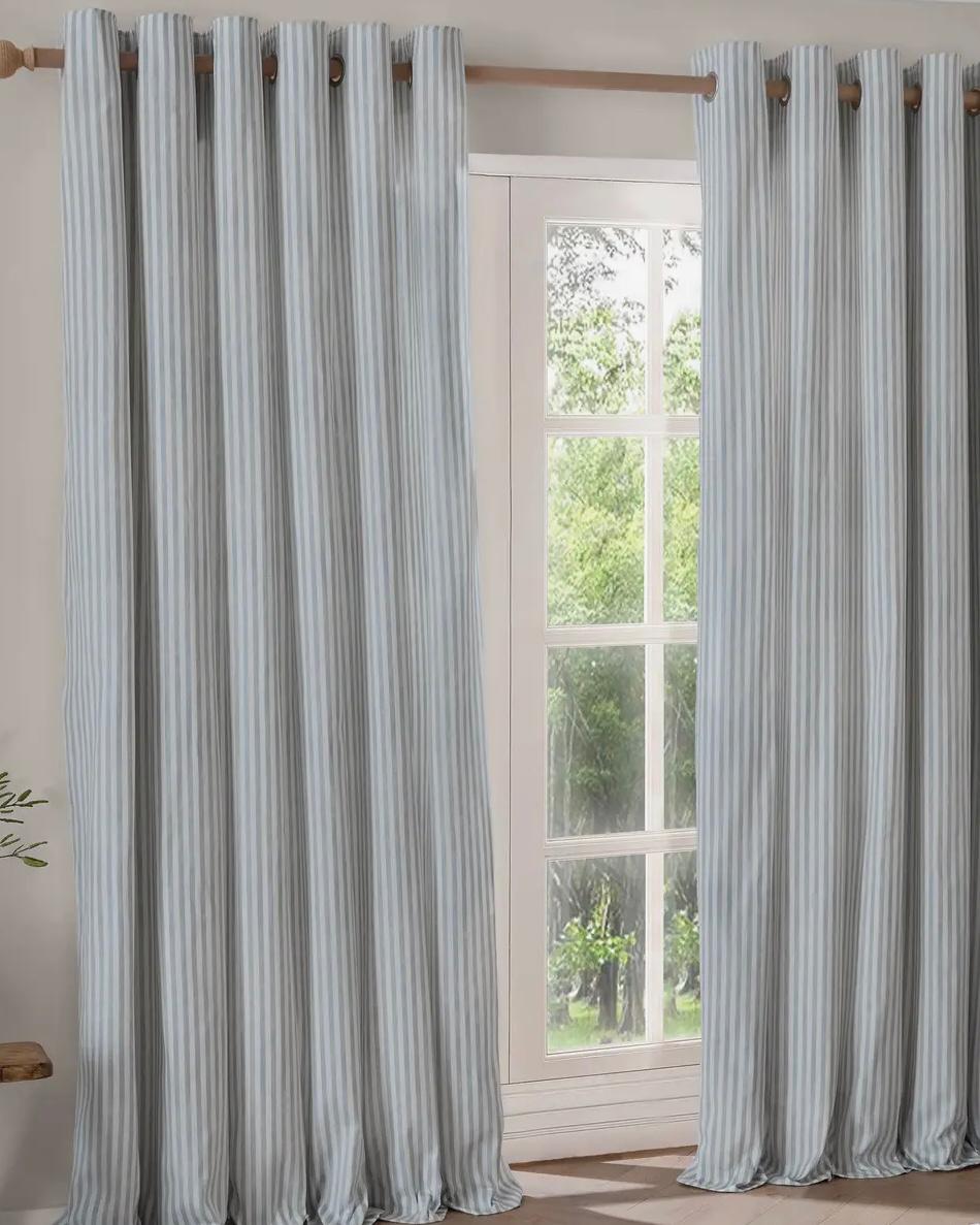 Riva Home Ocean Blue and black striped blackout eyelet curtains hanging in a living room, soft furnishings for window insulation.