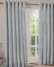 Riva Home Ocean Blue and black striped blackout eyelet curtains hanging in a living room, soft furnishings for window insulation.