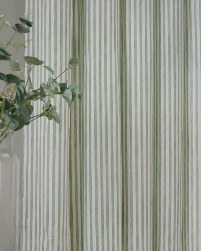 Yard Sage Green and black striped blackout eyelet curtains from Riva Home hanging in a living room window.