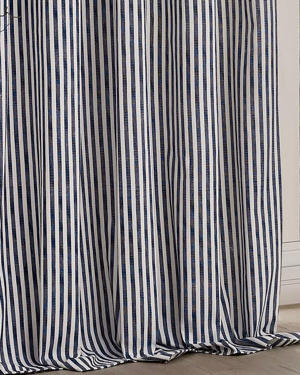 Navy blue and black striped blackout eyelet curtains by Riva Home hanging in a living room window, soft furnishings for privacy and style.