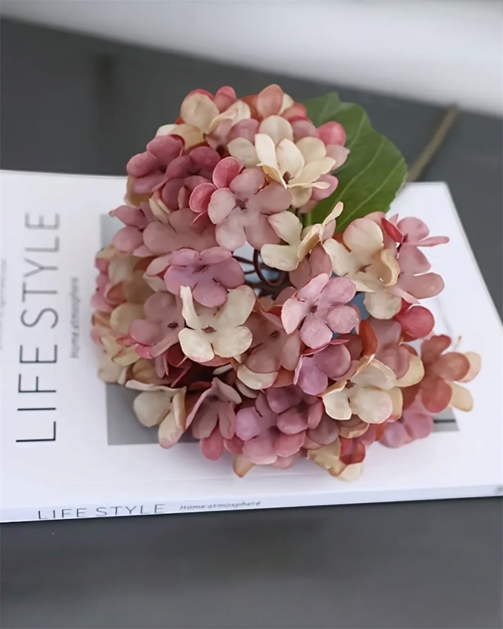 Artificial short pink hydrangea stem from Starlight Express, featuring vibrant pink blooms and green foliage for decorative arrangements.