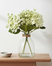 Artificial white flower arrangement in a clear glass vase, crafted by Heaven Sends, perfect for elegant home decor.