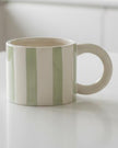 Sage green and white striped ceramic mug from Heaven Sends, with a stylish, curved handle and modern design.