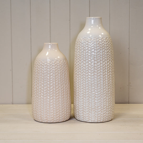White leaf-patterned ceramic vase with a glossy finish and narrow bottle-shaped neck
