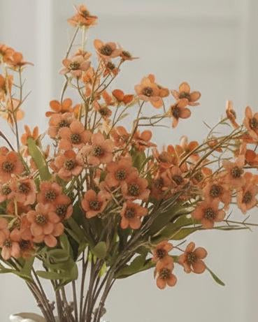 Orange artificial daisy flower stem from Starlight Express, showcasing vibrant petals and green foliage for decorative use.