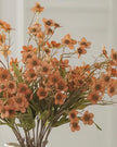 Orange artificial daisy flower stem from Starlight Express, showcasing vibrant petals and green foliage for decorative use.