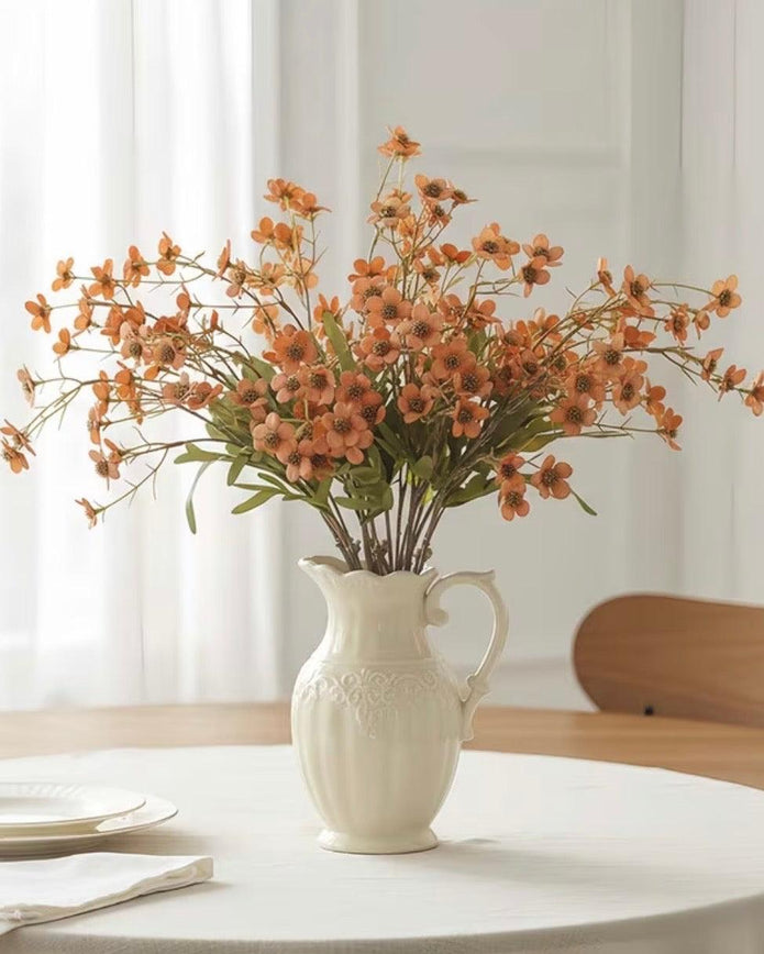 Orange artificial daisy flower stem from Starlight Express, showcasing vibrant orange petals and green foliage.