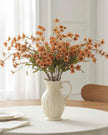 Orange artificial daisy flower stem from Starlight Express, showcasing vibrant orange petals and green foliage.