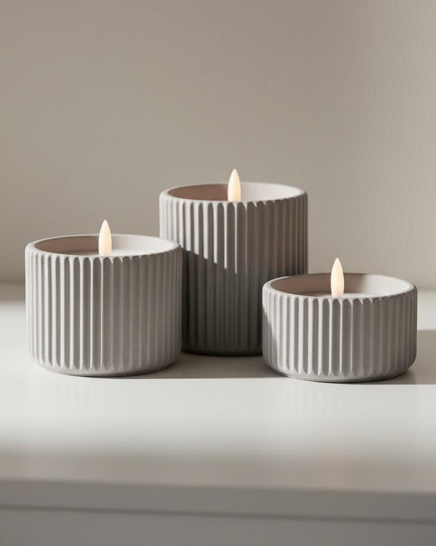 Ribbed natural stone LED candle from Hill Interiors, glowing softly for elegant home decor ambiance.