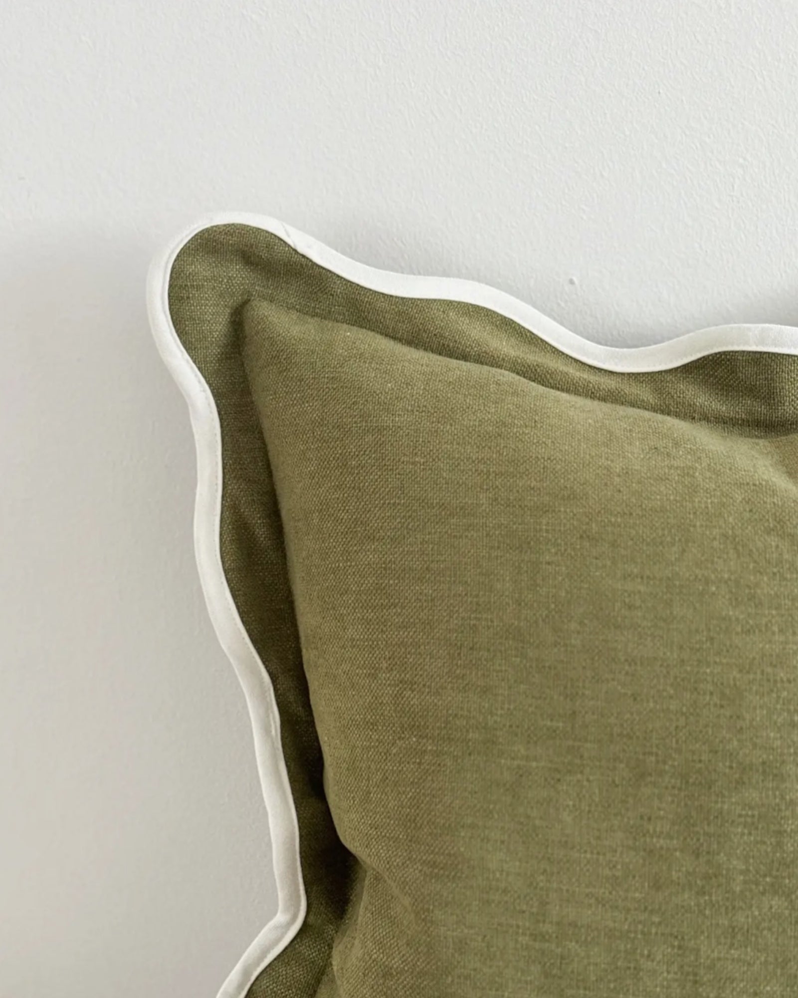 Olive green square cushion cover with scalloped edges, soft furnishings by Ellenvale Trade, shown on a sofa.
