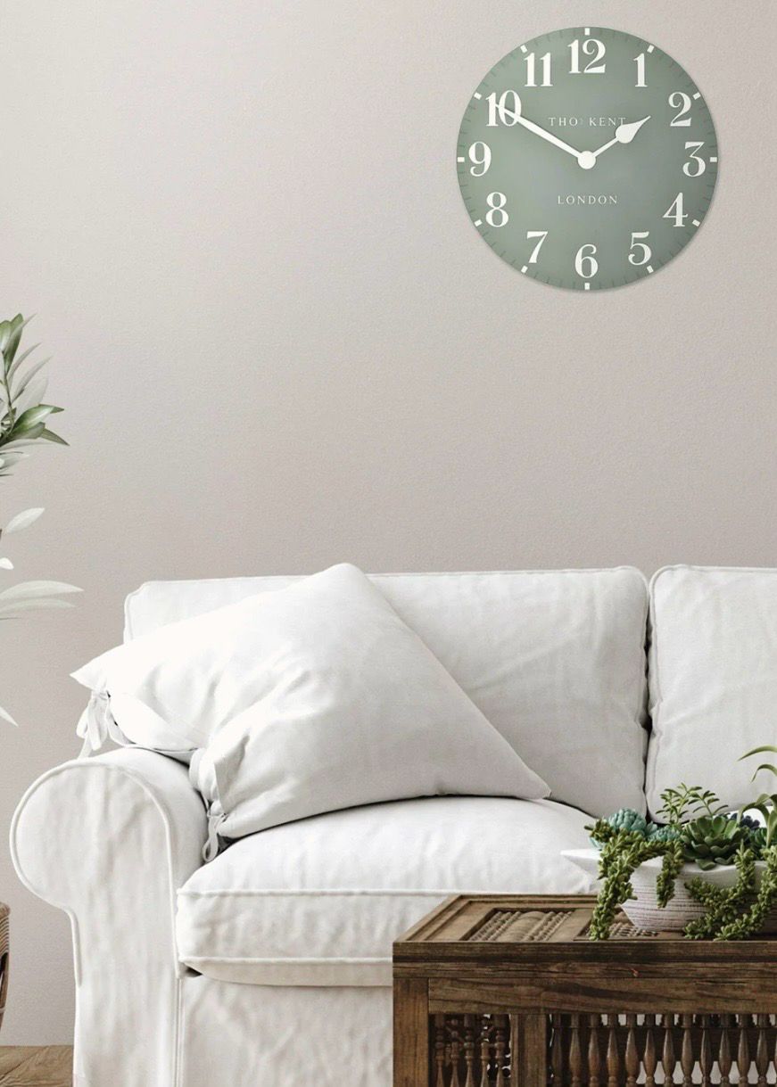 Thomas Kent 12-inch Arabic wall clock in seagrass green with black numerals, mounted on a plain wall.