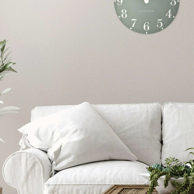 Thomas Kent 12-inch Arabic wall clock in seagrass green with black numerals, mounted on a plain wall.