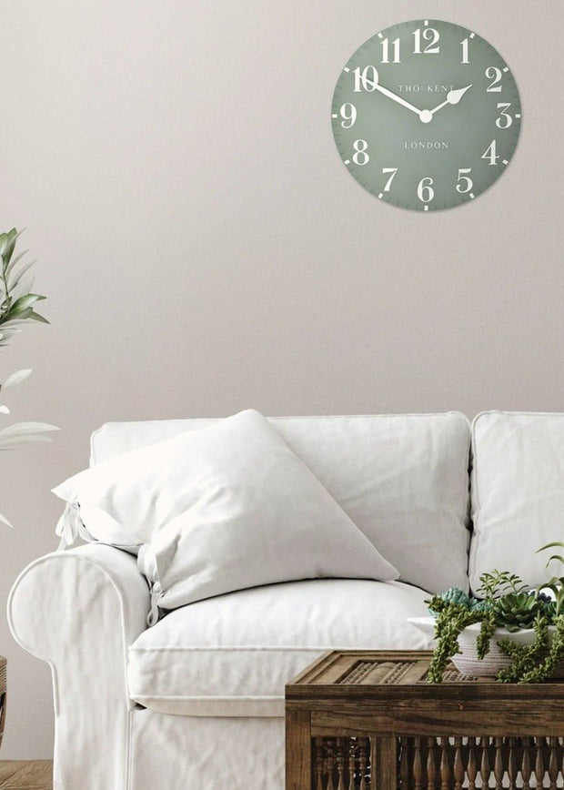 Thomas Kent 12-inch Arabic wall clock in seagrass green with black numerals, mounted on a plain wall.