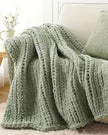 Soft sage green chunky chenille knit throw blanket by Starlight Express, showcasing its cozy, textured fabric and plush appearance.