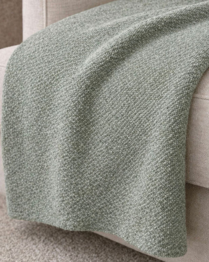 Malini Stello tactile green blanket throw draped over a sofa, showcasing soft, cozy furnishings for home decor.