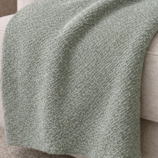 Malini Stello tactile green blanket throw draped over a sofa, showcasing soft, cozy furnishings for home decor.