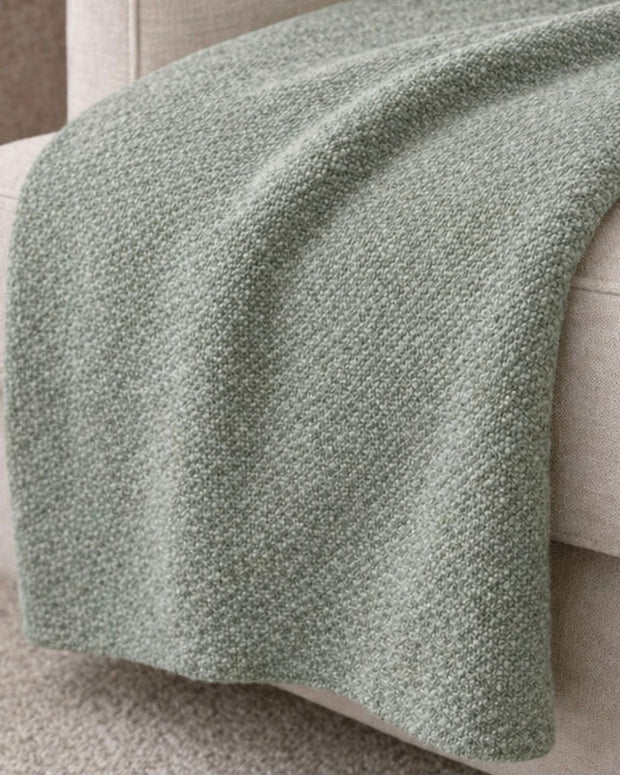 Malini Stello tactile green blanket throw draped over a sofa, showcasing soft, cozy furnishings for home decor.
