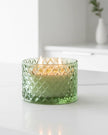 Embossed green glass candle with Corsia scent by Candlelight Products Ltd, decorative candle for ambient lighting.