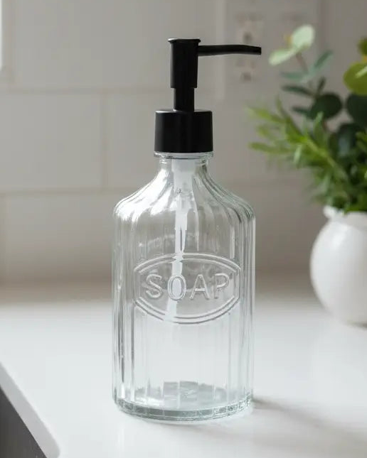 Clear ribbed glass soap dispenser bottle labeled 