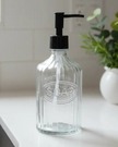 Clear ribbed glass soap dispenser bottle labeled 