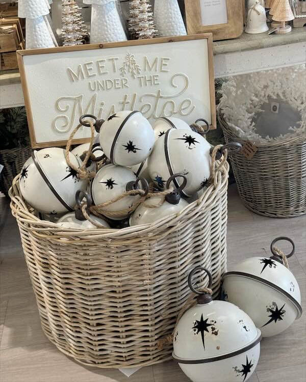 Decorative white balls with black patterns in a woven basket, with a sign reading 'Meet me under the Mistletoe' in the background.