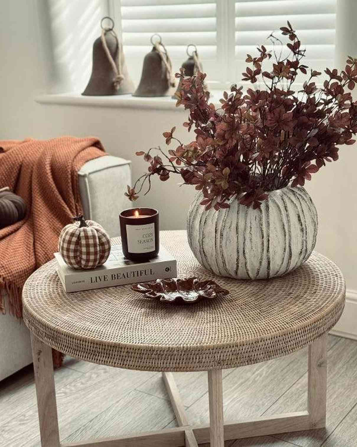 Round woven coffee table with decorative items in a cozy living room.