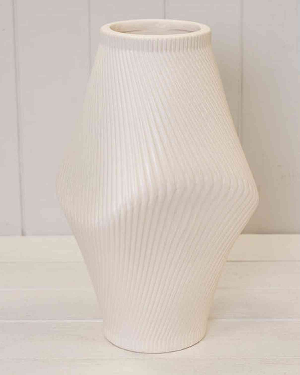 White ribbed vase on a white surface with a light gray background