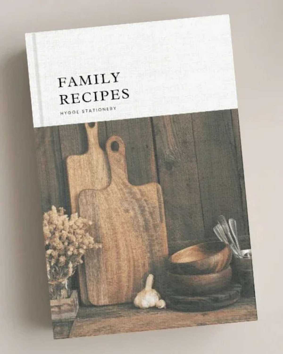 Book titled 'Family Recipes' with wooden cutting boards and bowls on a wooden shelf.