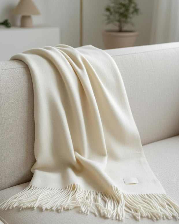 Ellenvale Trade Della Cream soft knit luxury throw blanket with fine texture, draped neatly on a cozy sofa.
