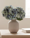 Artificial short dusky blue hydrangea stem from Starlight Express, showcasing lush blooms and vibrant color in a natural arrangement.