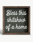 Decorative sign with text 'Bless this shitshow of a home' on a white background