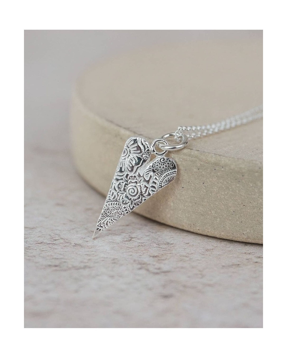 Silver necklace with an ornate pendant on a light background