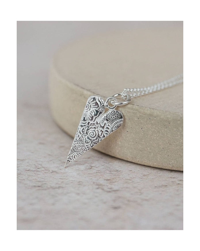 Silver necklace with an ornate pendant on a light background