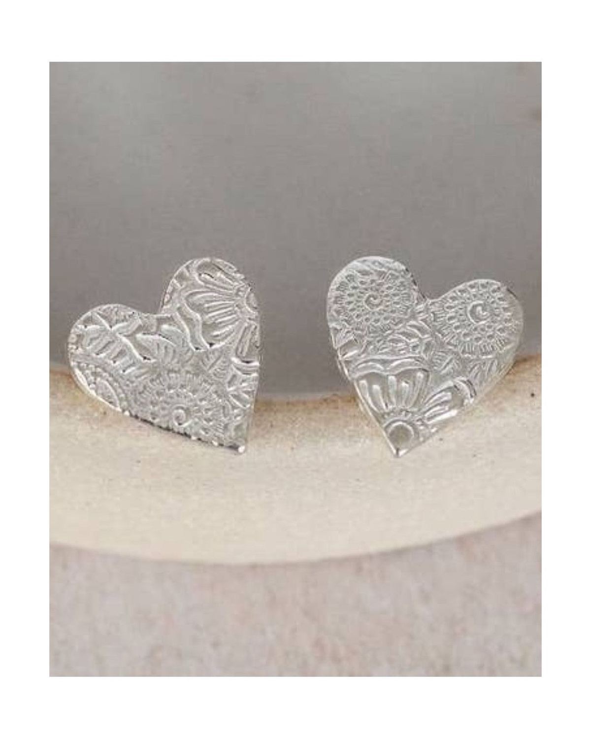 Silver heart-shaped earrings on a white ceramic dish