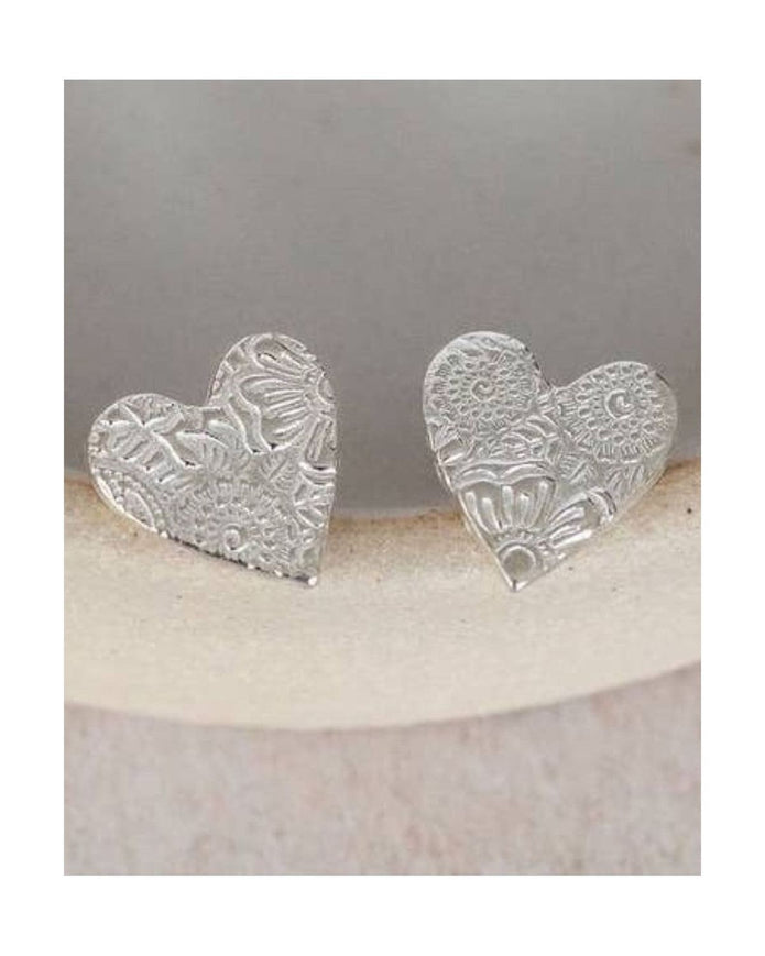 Silver heart-shaped earrings on a white ceramic dish