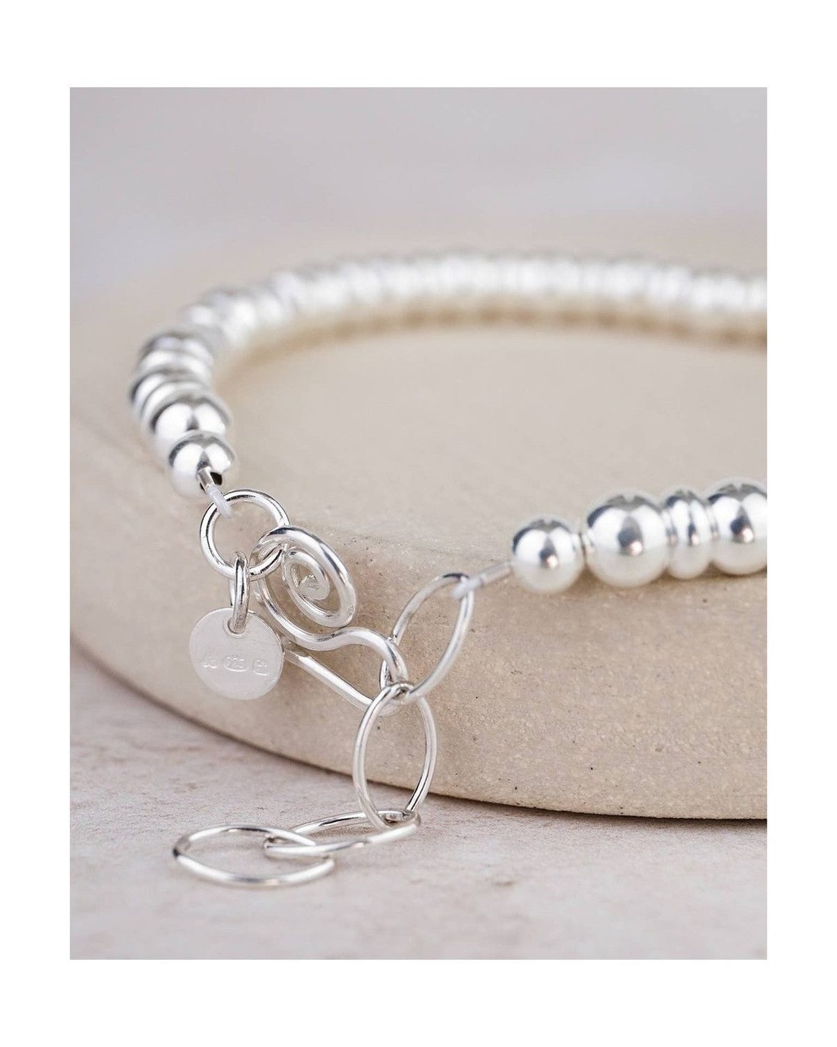Silver beaded bracelet with a charm on a light background
