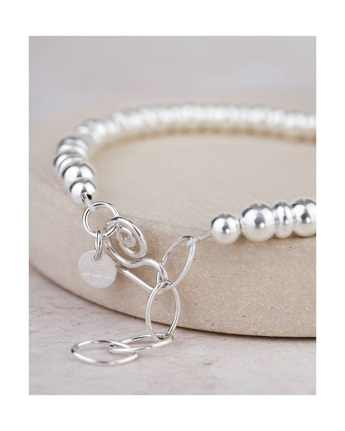 Silver beaded bracelet with a charm on a light background