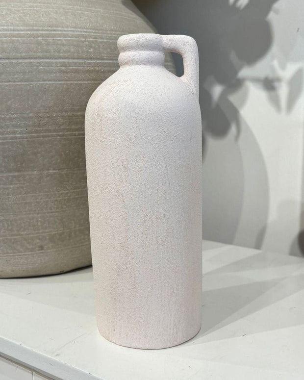 White ceramic bottle on a white surface with a neutral background