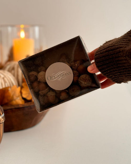 Box of chocolates held by a person with a blurred candle in the background